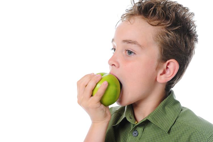 menino comendo maçã verde