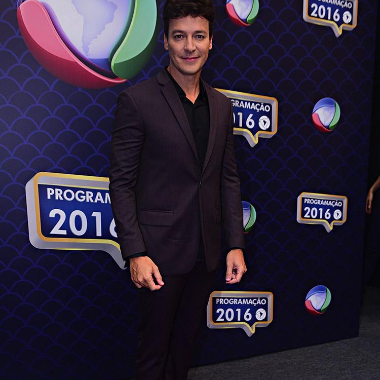 O apresentador Rodrigo Faro usando Terno Preto, olhando para a frente e sorrindo