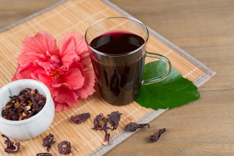 xícara com chá de hibisco e flores em volta