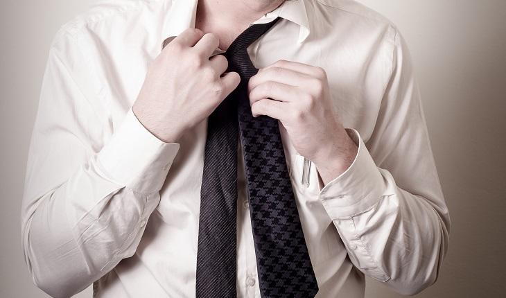 A foto mostra um homem tirando sua gravata. Se vestir de lhos fechados ajuda a exercitar o cérebro