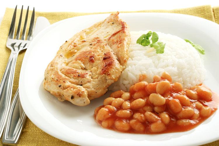 Prato simples com arroz, feijão e peito de frango empanado.
