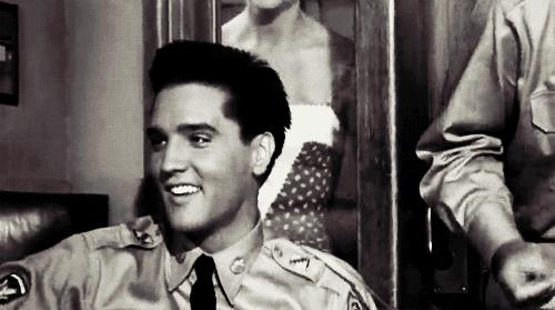 gif do cantor Elvis Presley sorrindo e cantando com roupa do exército Mercury