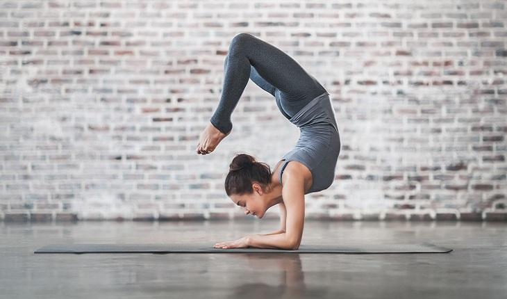 A foto mostra uma mulher praticando ioga para fugir da rotina