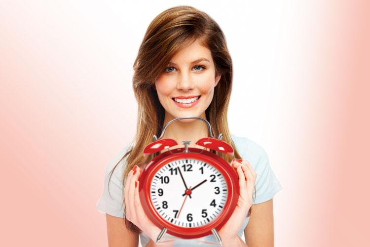 mulher sorrindo segurando um relógio/despertador vermelho em suas mãos