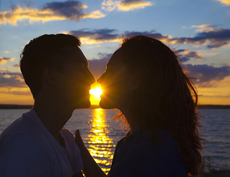 Casal se beijando com por do sol no fundo