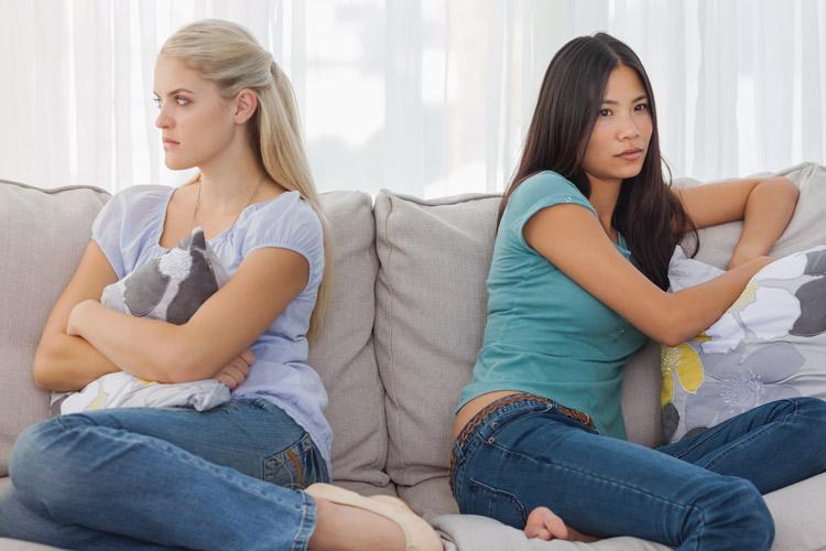 duas mulheres rivais sentadas em um sofá uma de costas para a outra