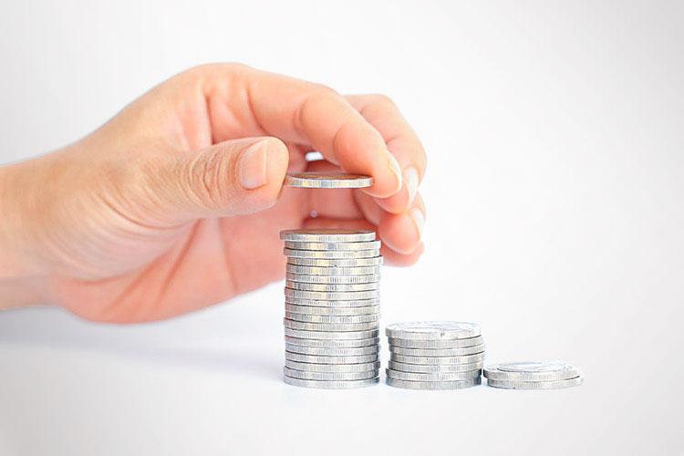 mão colocando uma moeda em um montinho de moedas