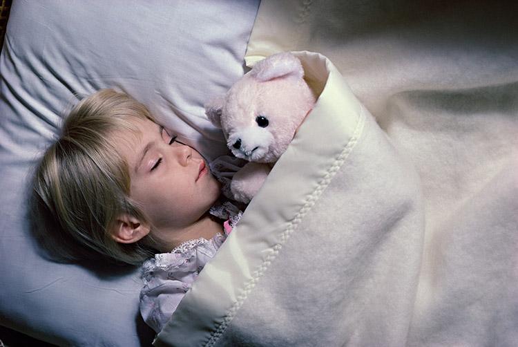 menina loira dormindo cama ursinho brinquedo 