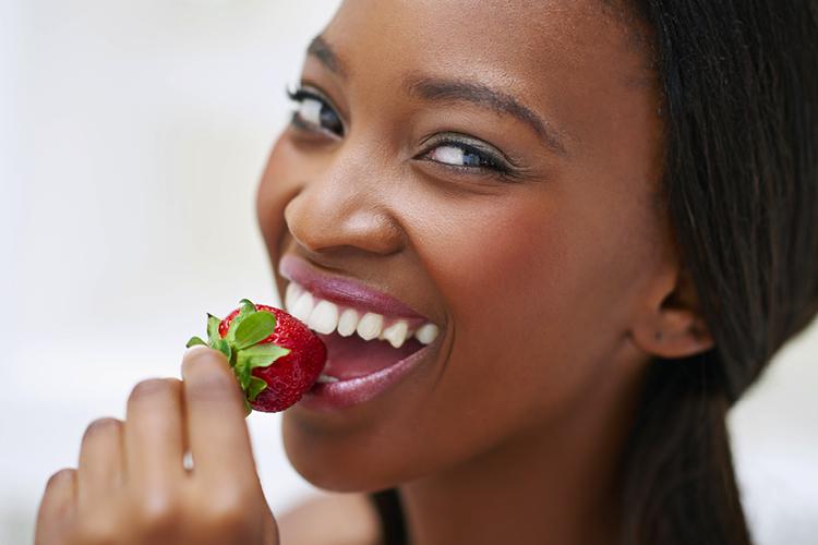 Ingredientes certos: mulher comendo morango sorrindo