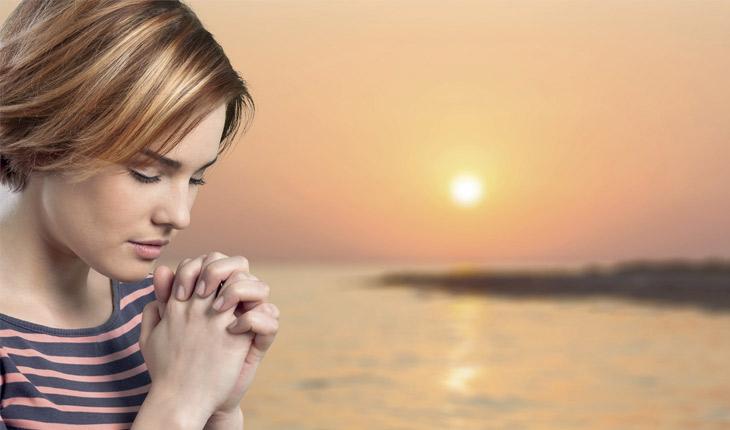 mulher orando no pôr do sol