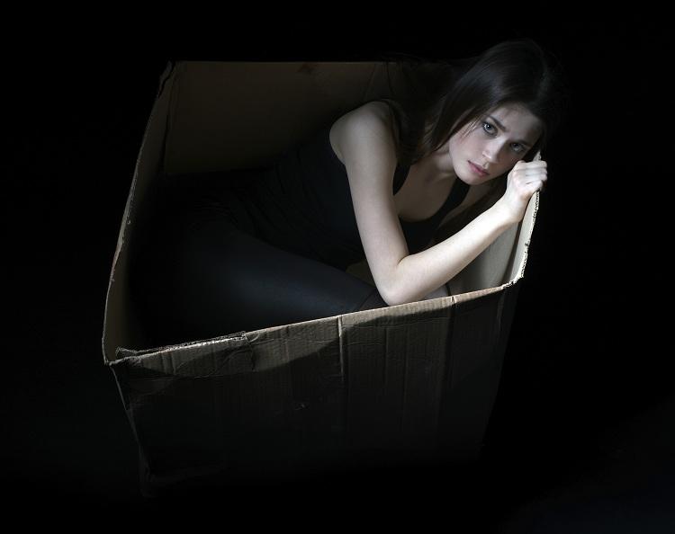 mulher dentro de uma caixa num fundo preto 