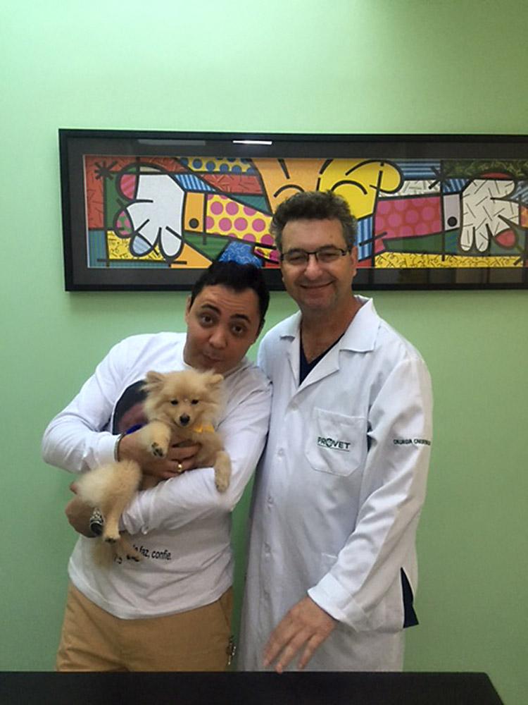 homem segurando um cachorro ao lado de um veterinário