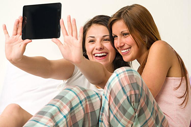 duas amigas sorrindo tirando selfie com o tablet