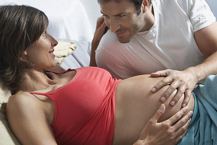 mulher grávida homem passando a mão na barriga