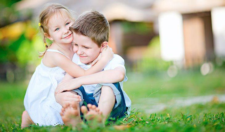 Dia das Crianças. Na foto, menina e menino abraçados na grama