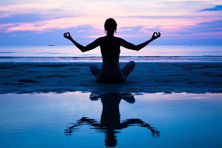 mulher-meditação-água-mar-céu-colorido