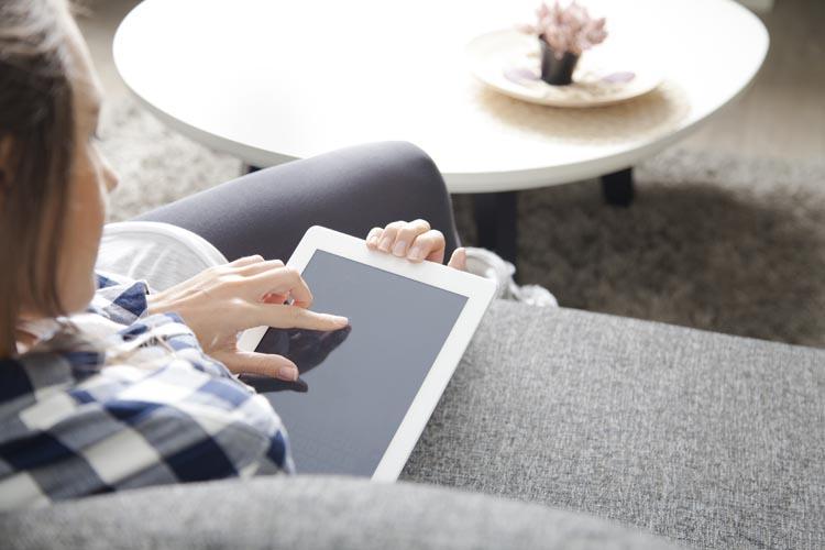 mulher-sentada-sofá-digitando-tablet-iphone e ipad-aplicativo-banca