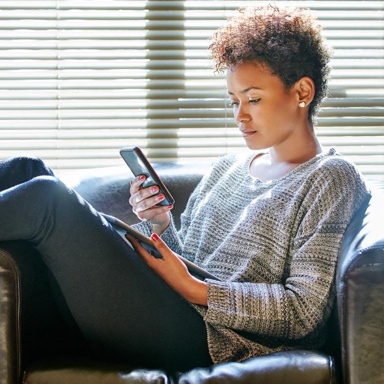 mulher-sentada-sofá-olhando-celular-smartphone-segurando-tablet-iphone e ipad-configurações