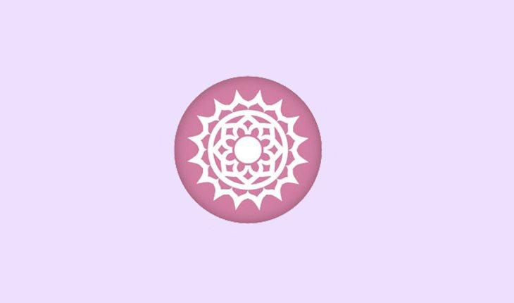 Na foto há o símbolo do chakra conorário. É um círculo rosa com o desenho de um sol com muitas pontas no centro, feito em branco.