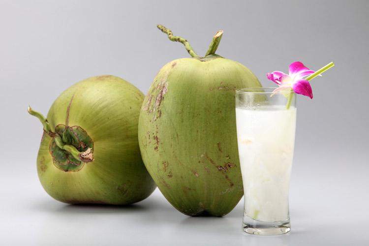 dois cocos inteiros e um copo com água de coco
