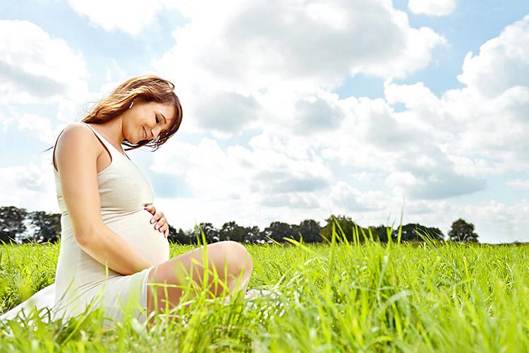 mulher-gravida-sentada-gramado-ar-livre