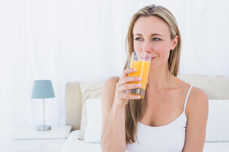 mulher loira bebendo suco de laranja