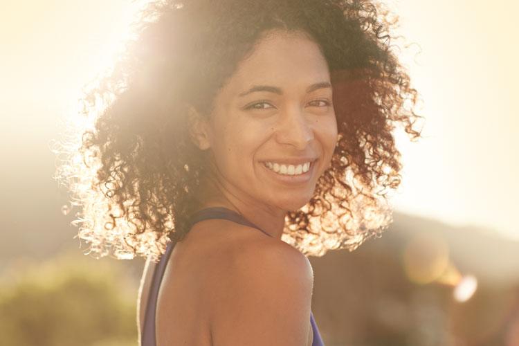 mulher negra com blusinha azul sorrindo, empoderamento feminino