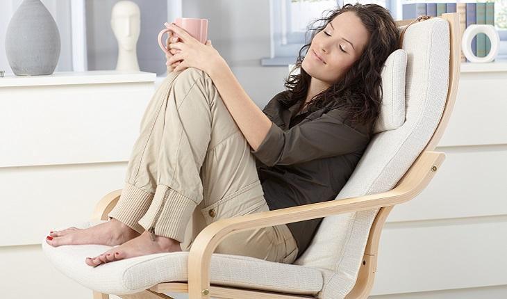 A foto mostra uma mulher descansando para recuperar o foco. Ela esta descalça sentada em uma cadeira