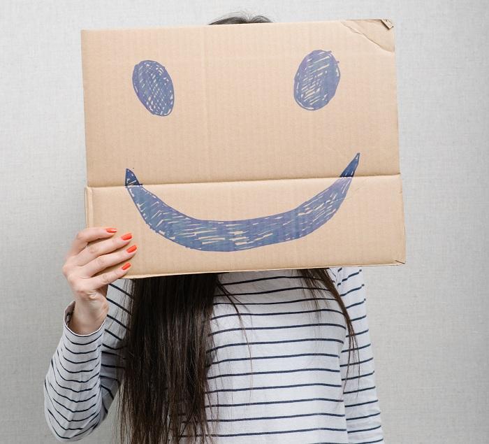 mulher segurando uma caixa de papelão com um sorriso desenhado simbolizando ego e autoafirmação