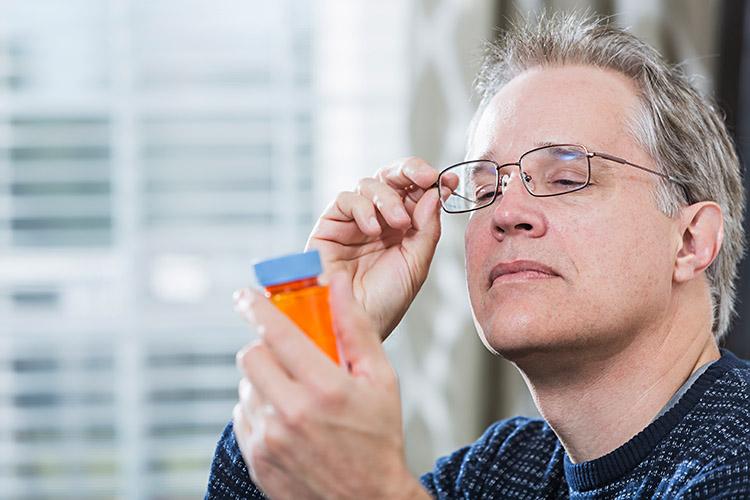 homem oculos olhando rotulo remedio