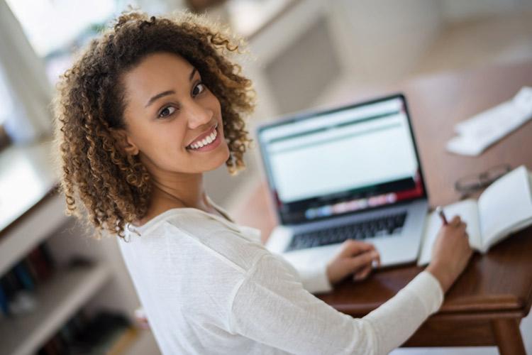 moça negra, sorrindo enquanto usa o computador