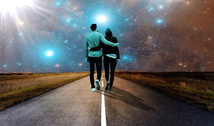 casal de espíritos andando abraçados por uma estrada com um céu estrelado ao fundo