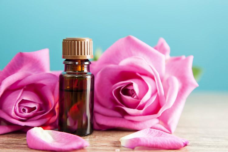 Frasco de essência com rosas ao lado, indicando aromaterapia