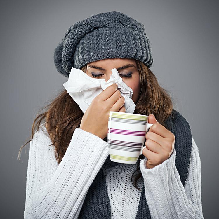 Mulher, com gripe, assoando o nariz no lenço