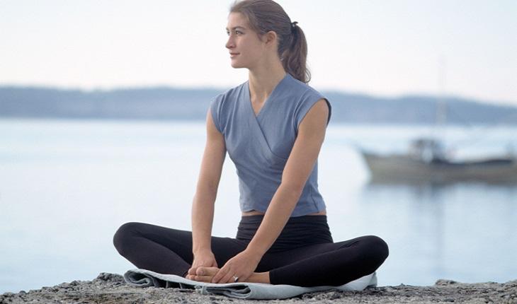 Mulher loira meditando em uma rocha para combater a ansiedade
