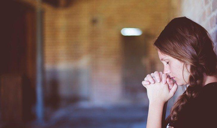 mulher rezando com olhos fechados