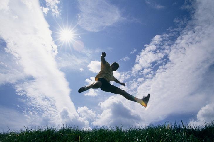 homem dando um salto enquanto realiza exercícios físicos na grama