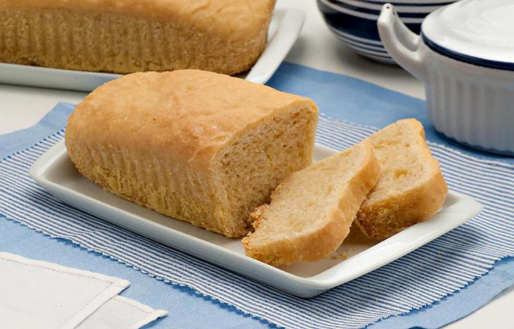Pão salgado sem glúten e sem lactose com duas fatias cortadas disposto em um prato retangular branco