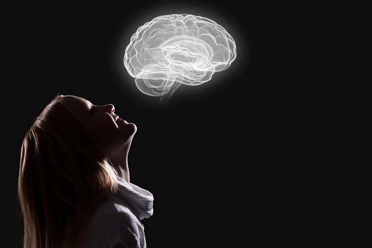 A foto mostra uma mulher olhando para o desenho de um cérebro acima dela, como se estivesse observando os benefícios do mindfulness no órgão