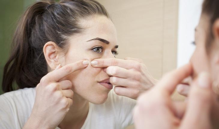Foto de mulher com acne, se olhando no espelho.