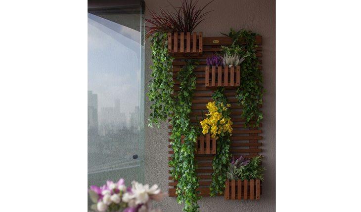 Na foto há um jardim vertical de madeira com os vasos feitos de madeira também. Está em uma parede de varanda.