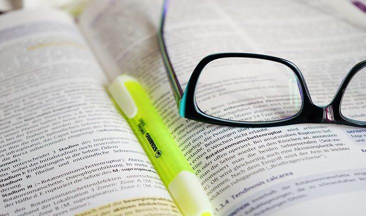 foto de um grifa-texto e de um óculos em cima de um livro