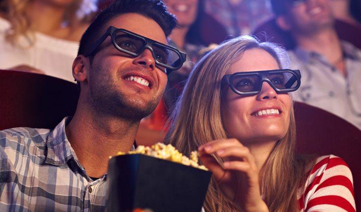 Casal assistindo filme e comendo pipoca em cinema 3d