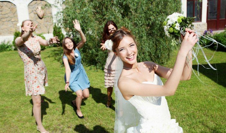 Mulher jogando buquê-de-noiva para amigas no casamento