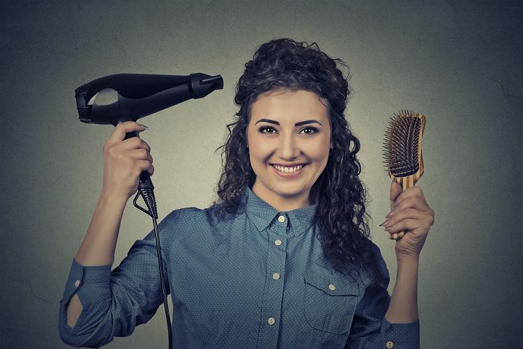 Mulher segurando secador e escova de cabelo