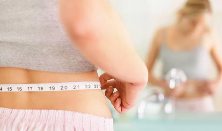 mulher medindo sua cintura com fita métrica