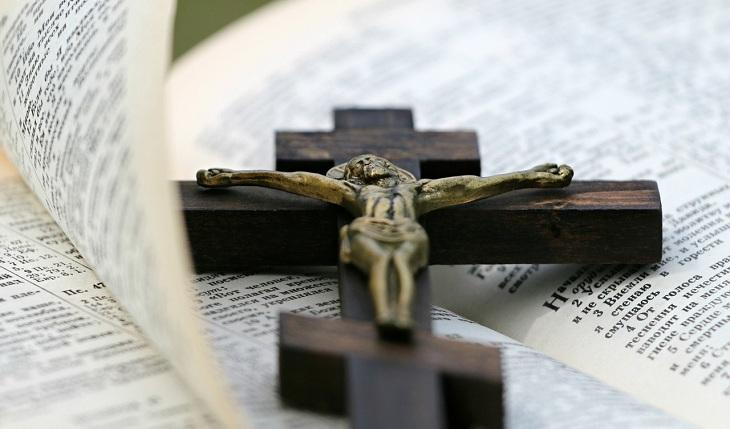 Na imagem, um crucifixo está em cima de uma bíblia ao vento. Novena de santa rita de cássia.