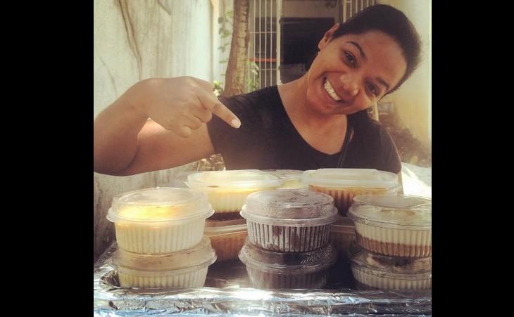 Paola mostra a fotografia de uma mulher que vende comidas na rua e aponta para diversos bolos em potes pequenos