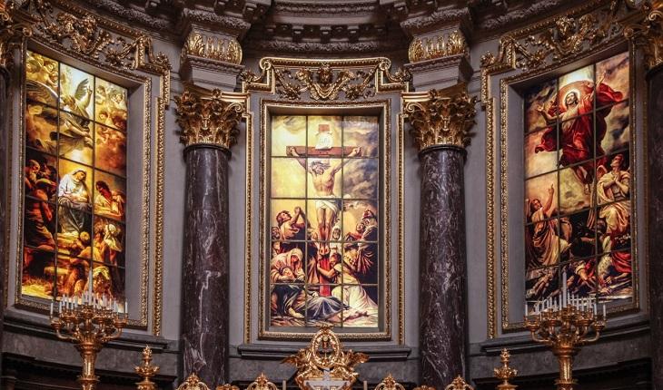 Na imagem, um altar de igreja com várias de imagens de histórias de jesus e outros santos pintados nos vitrais. Novena de santa rita de cássia.