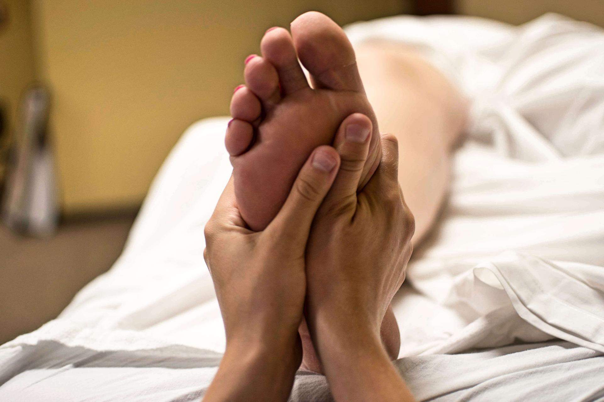 A foto mostra uma mulher recebendo massagem nos pés
